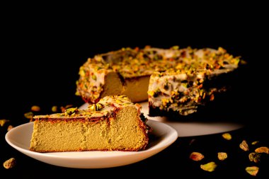 Siyah arka planda fıstıklı cheesecake. Fıstıklı lezzetli tatlı. Fıstık kreması, peynir, fıstık, sos..