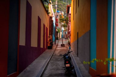 Narrow streets in a colorful town on the Caribbean coast. Motorbike in the street. clipart