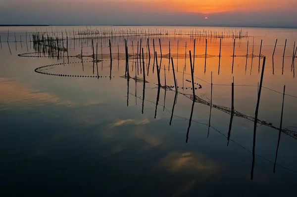 stock image golden sunset with warm colors in the albufera lake in Valencia, Spain with fishing traps on the water