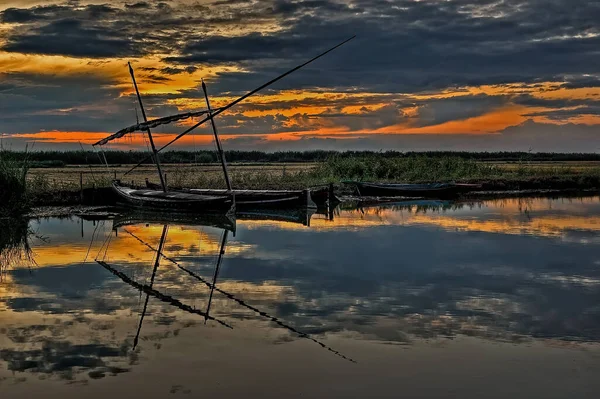 İspanya, Valencia 'da Albufera Gölü kıyısında günbatımında Latin yelkenli geleneksel balıkçı tekneleri
