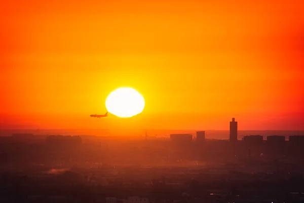 Uçak Valencia 'daki havaalanına inmek için yaklaşıyor. Uçak arkasında Güneş ve arka planda şehrin ufuk çizgisi var.