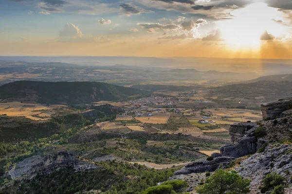 İspanya 'da gün batımında gökyüzünde bulutlarla kırsalın yukarısından görülen küçük bir köy.