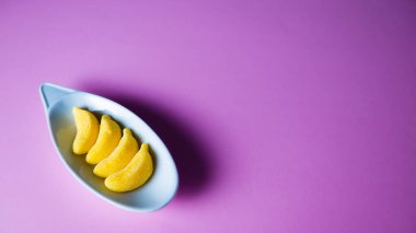 banana gummies on a plate on a pink background.