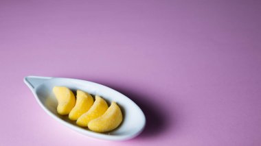 banana gummies on a plate on a pink background.