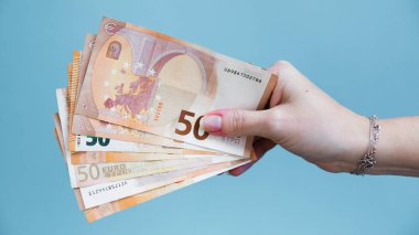 Avro banknotlarını ve parayı tutan el.