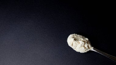 Siyah arka planda bir kaşık pudra şekeri. Boşluğu kopyala.