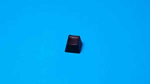 Black \'\'escape\'\' keyboard key isolated on blue background Top view. Copy space.
