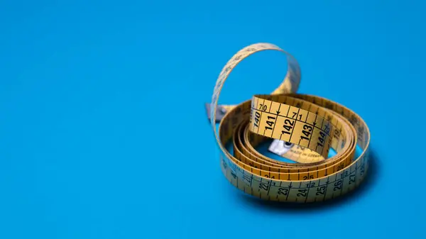 stock image yellow measuring tape on a blue background