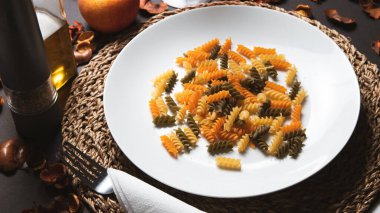 Fusilli makarna, beyaz tabakta, arka planda..