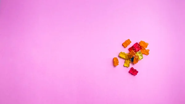 Pembe arka planda renkli ayıcık şekerleri. Üst görünüm.
