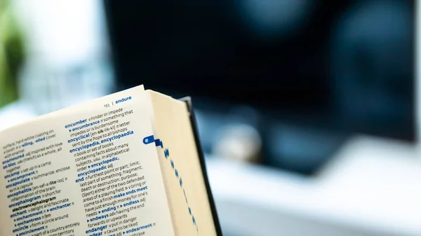 close-up of a book with a pen and a laptop