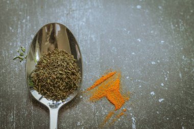 Siyah arka planda baharatlı ve otlu kaşıklar. Yemek ve yemek malzemeleri..