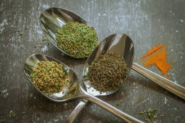 Siyah arka planda baharatlı ve otlu kaşıklar. Yemek ve yemek malzemeleri..