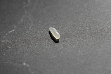 Bulanık bir arkaplanı olan karanlık bir yüzeyde pirinç hapının yakın çekimi.