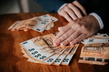 Avro banknotlarını sayan adam. İşadamı tahta masada para sayıyor..