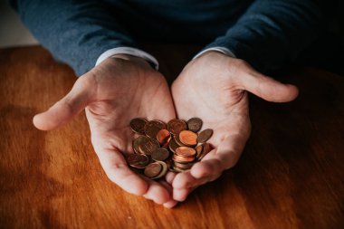 Bir avuç bozuk para tutan bir adamın elleri. Tasarruf kavramı.