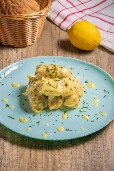 Traditional Greek cabbage rolls (Lahanodolmades) with ground beef, rice and cream sauce on a wooden table