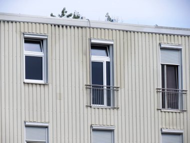 Plastik pencereleri ve panjurları olan modern bir konut binasının cephesi.