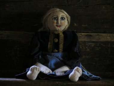 Ahşap bir duvarın arkasında eski bir bez bebek..