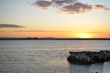 Siwa, Mısır - 7 Ekim 2022: Siwa Mısırdaki fetnas adasının yanındaki Siwa vahasındaki suya güneş ışığı yansıyan güzel sarı gün batımı manzarası.