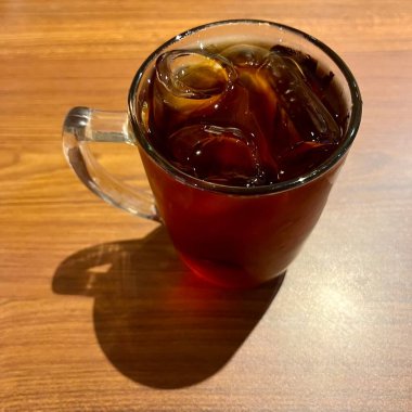 a glass of ice tea on a wooden table