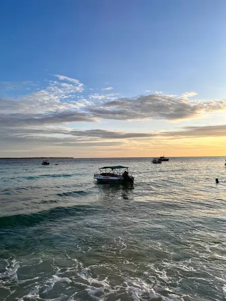 Suyun üzerinde yüzen bir tekneyi çevreleyen güzel pembe bir gökyüzü