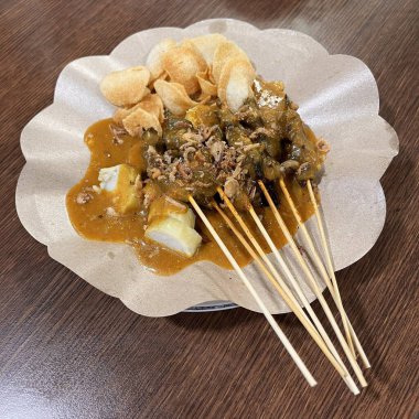 Sate Padang ya da Satay Padang sos, pirinç keki ve krakerle servis edilir.