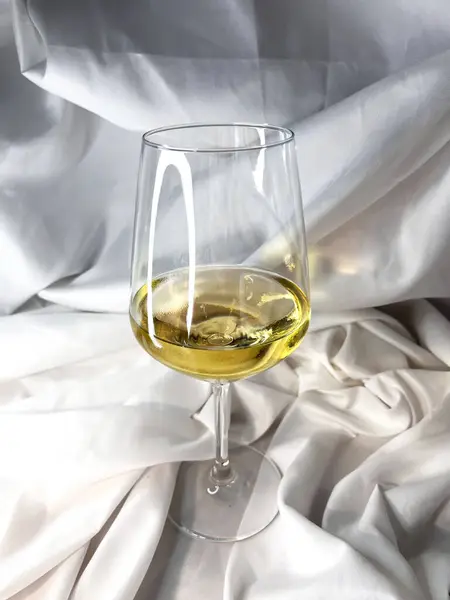 Beyaz tekstil arka planında beyaz şarap, beyaz sauvignon, beyaz bardak. Üst görünüm.