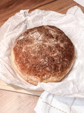 Taze pişmiş yuvarlak ekmek, ahşap bir masada, kağıt fırınında..