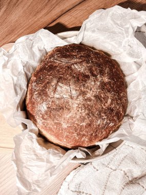 Taze pişmiş yuvarlak ekmek, ahşap bir masada, kağıt fırınında..