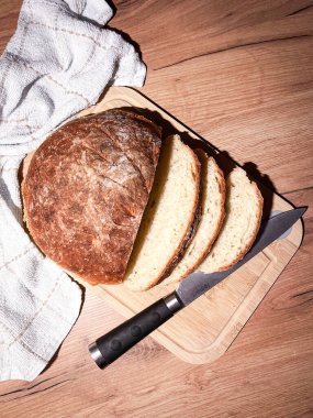 Ekmek, geleneksel ekşi ekmek. Tahta bir masada bıçakla dilimlenmiş..