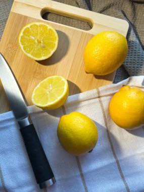 Tahtada bıçak, bej ve beyaz kumaş olan taze limonlar. Atmosferik fotoğraf