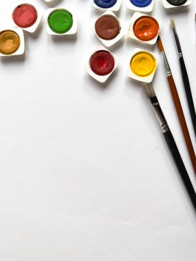 Beyaz arkaplanda suluboya boya seti ve fırçalar