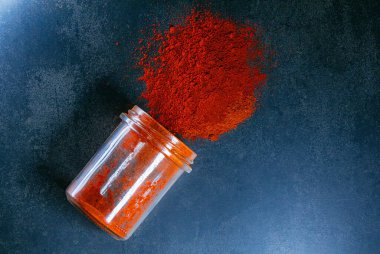 Kırmızı biber ve mavi arka planda bir kavanoz baharat.