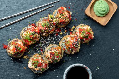 Suşi tahtada zencefil, soya sosu ve rafla yuvarlanıyor.