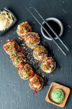 Suşi tahtada zencefil, soya sosu ve rafla yuvarlanıyor.