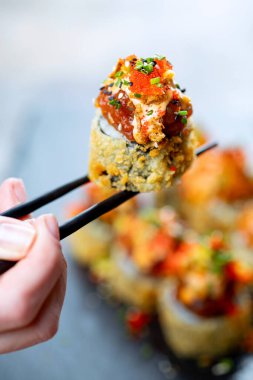 Arka planda siyah çubuklarda suşi yuvarlanıyor.