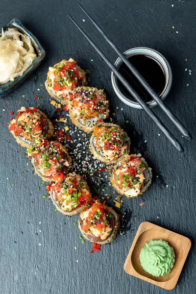 Suşi tahtada zencefil, soya sosu ve rafla yuvarlanıyor.