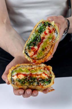 Sushi burgeri beyaz arka planda, eller kapalı.