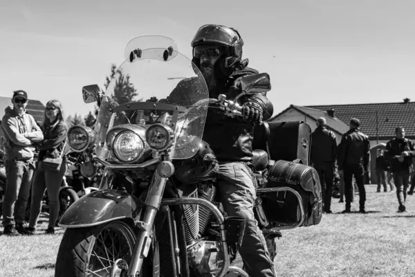 Motosikletler yeşil bir alanda, siyah-beyaz bir motor fuarında.