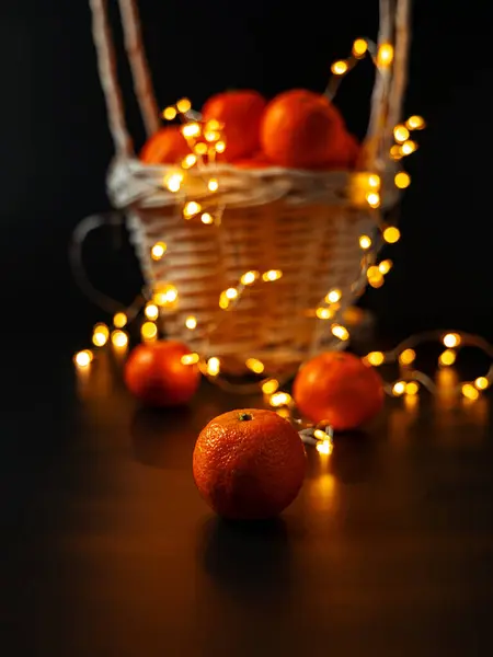 Arka planda mandalinalar ve yılbaşı arifesinde bir Noel ağacı olan sepet.