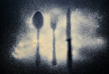 Koyu bir zemine serilmiş un çatal bıçak takımı.