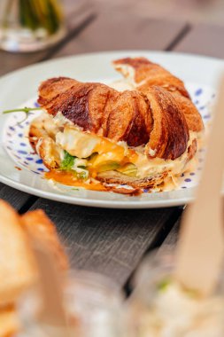 Krem peynirli kruvasan, kırmızı balık ve yumurta, Avrupa 'da bir atmosferik kafe yaz terasında sıcak bir kasabada kahvaltı, aksiyon, eller.