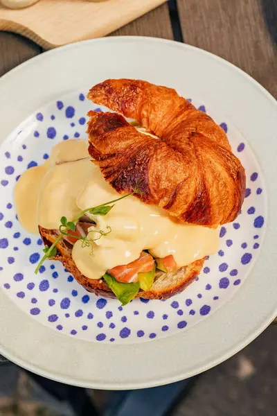 Krem peynirli kruvasan, kırmızı balık ve yumurta, Avrupa 'da bir atmosferik kafe yaz terasında sıcak bir kasabada kahvaltı, aksiyon, eller.