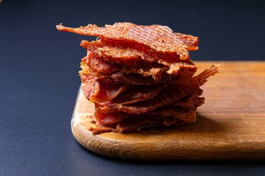 Tahtadaki kurutulmuş et parçaları koyu arka planda izole edilmiş.