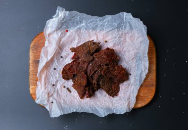 Tahtadaki kurutulmuş et parçaları koyu arka planda izole edilmiş.