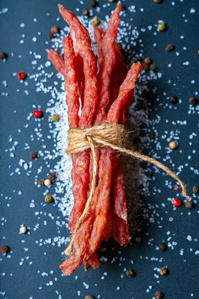 Kabanos et sosisleri koyu bir zemin üzerinde tuz ve baharatlarla izole edilmiş.