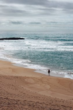 Portekiz 'in Sines şehrinde bir adam okyanus kıyısında yürüyor.