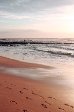 Portekiz 'in Vila Nova de Milfontes kasabasında Atlantik Okyanusu üzerinde insan ve günbatımı