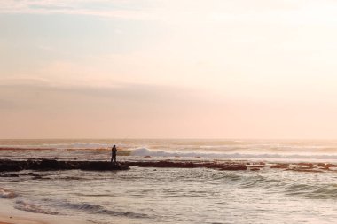 Portekiz 'in Vila Nova de Milfontes kasabasında Atlantik Okyanusu üzerinde insan ve günbatımı